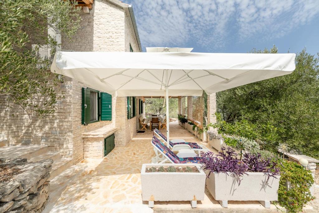 a white umbrella on a patio with chairs and a table at Villa Anita in Vela Luka