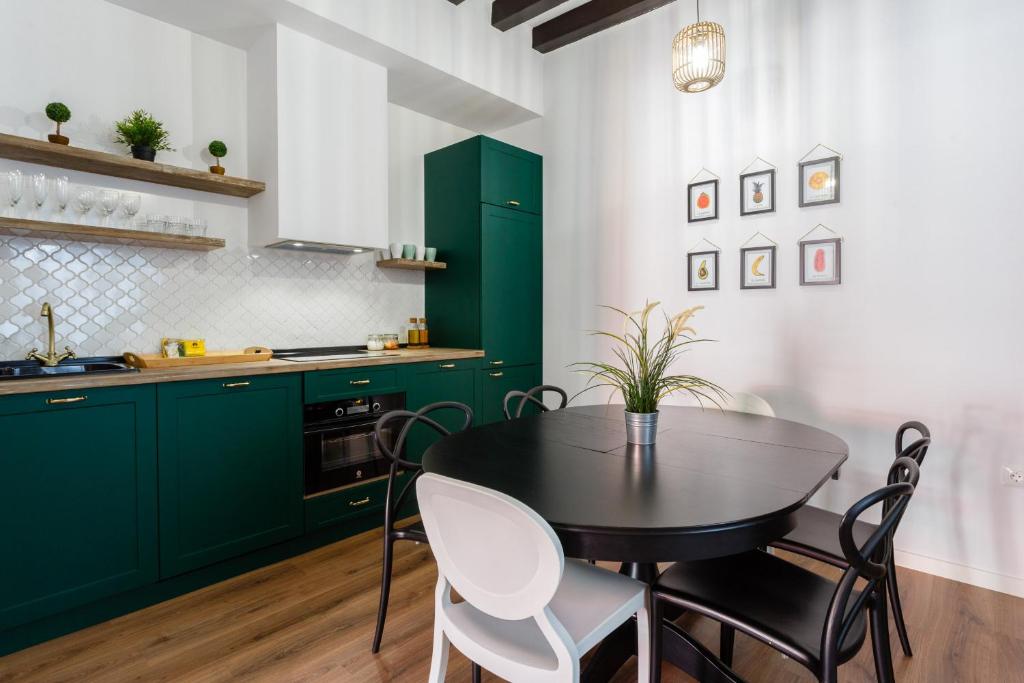 una cocina con armarios verdes, mesa y sillas en TACITA Family Home by Cadiz4Rentals, en Cádiz