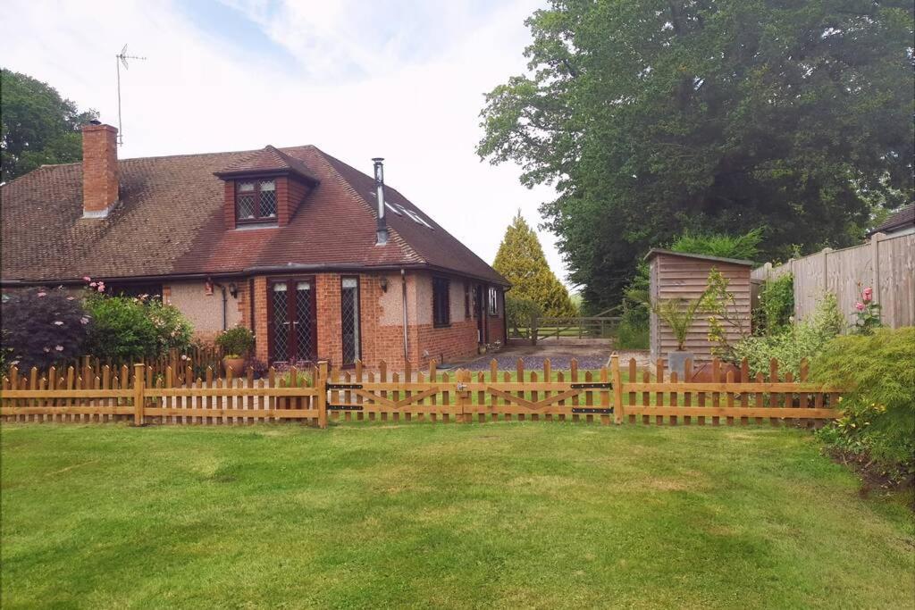 una valla de madera frente a una casa en Ashwood Holiday Cottage., en Ashford
