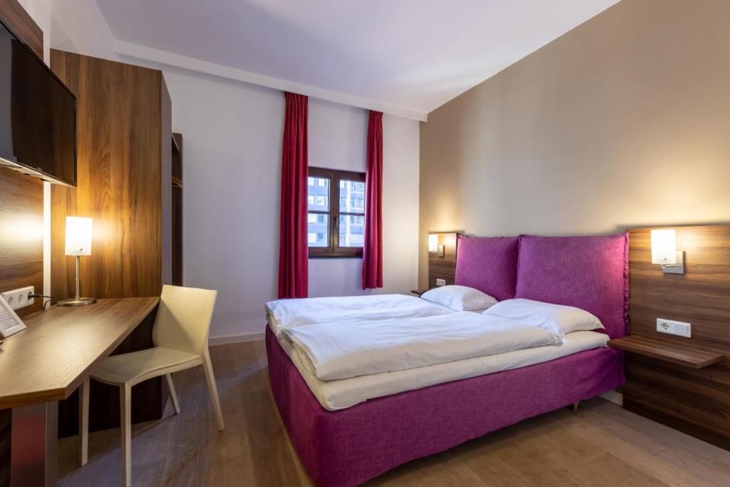 um quarto com uma cama roxa e uma secretária em Trip Inn Eden Antwerpen em Antuérpia