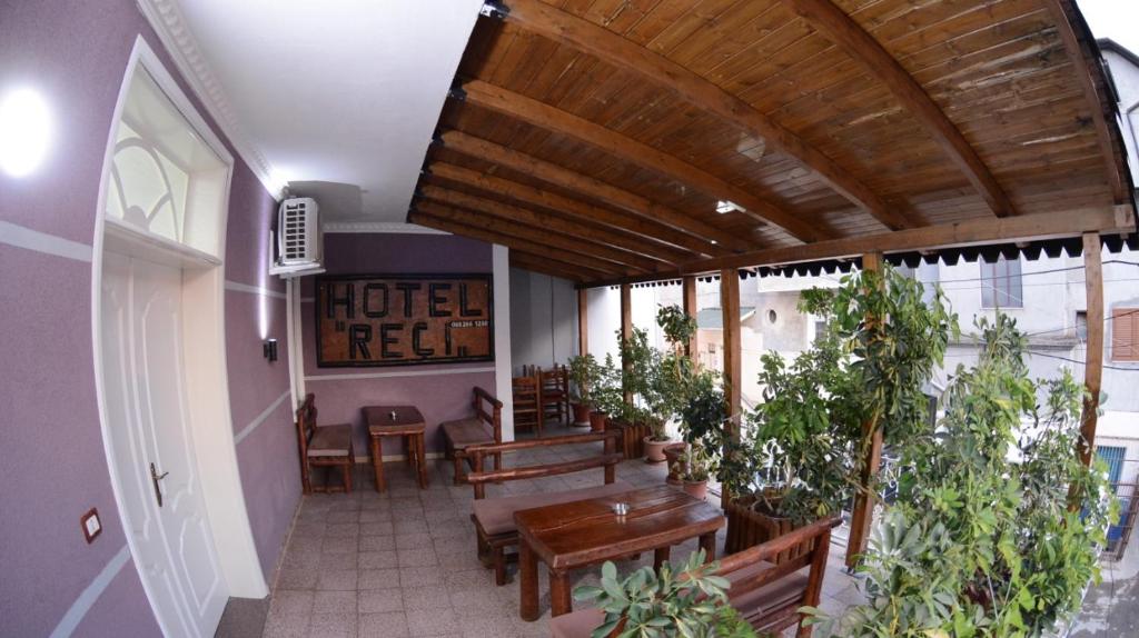 un ristorante con tavoli e panche in legno e piante in vaso di Hotel Reci a Peshkopi