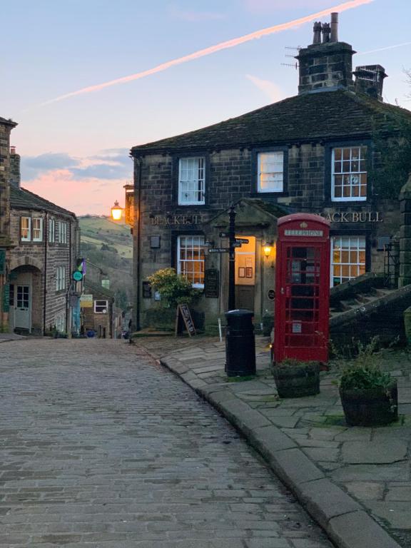 una vecchia cabina telefonica rossa di fronte a un edificio di Black Bull Inn a Haworth