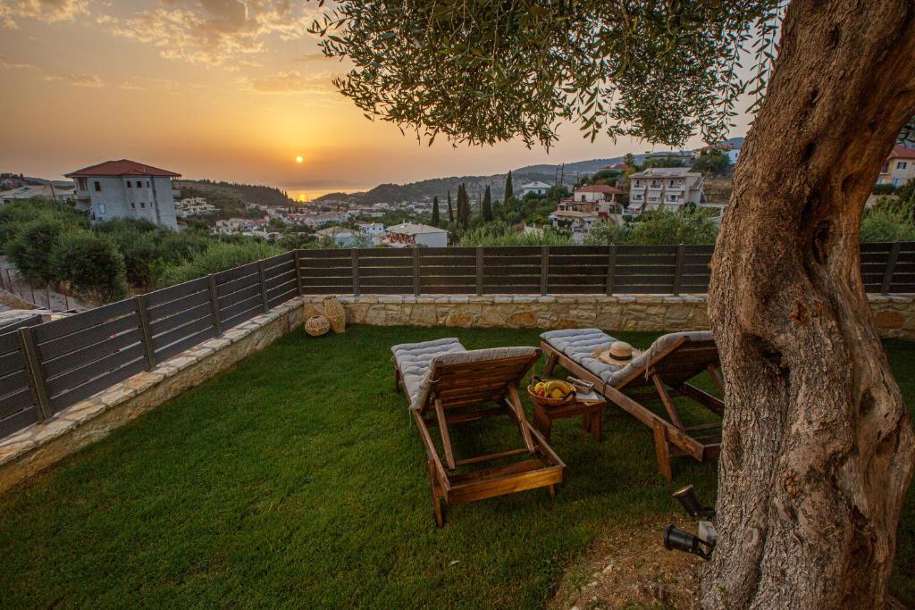 a table and chairs sitting on a lawn with a tree at Théa boutique villas sivota I in Sivota