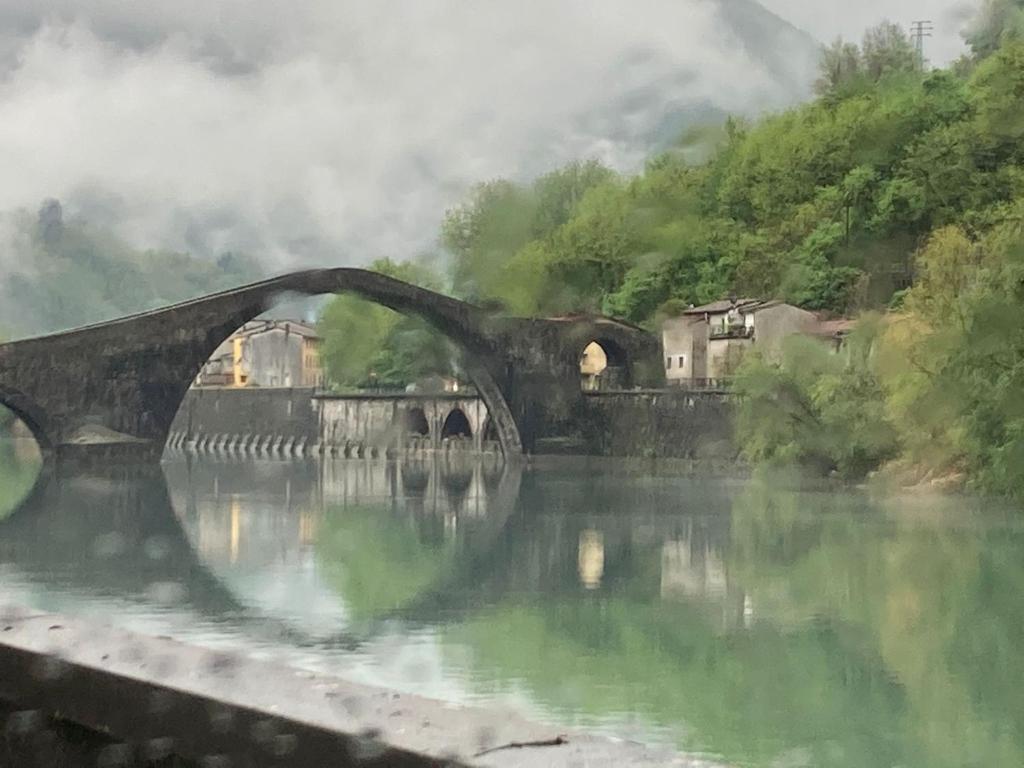 een schilderij van een brug over een rivier bij Torre del Duca in Bagni di Lucca