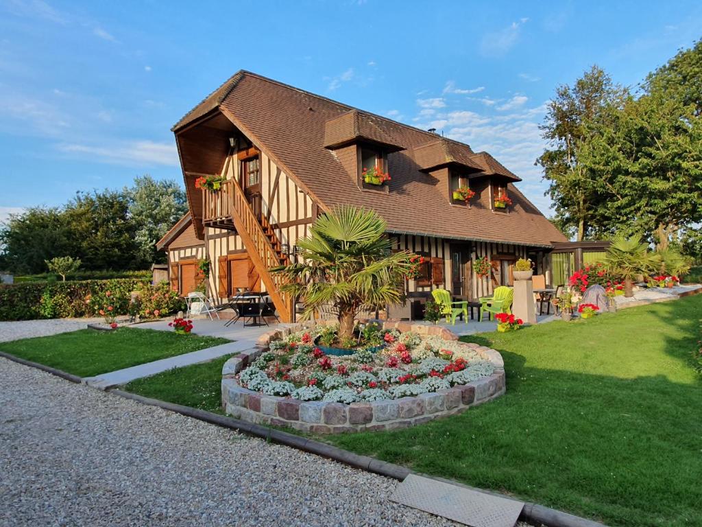 une maison avec un palmier dans un jardin dans l'établissement La mare aux canards, à Sassetot-le-Mauconduit