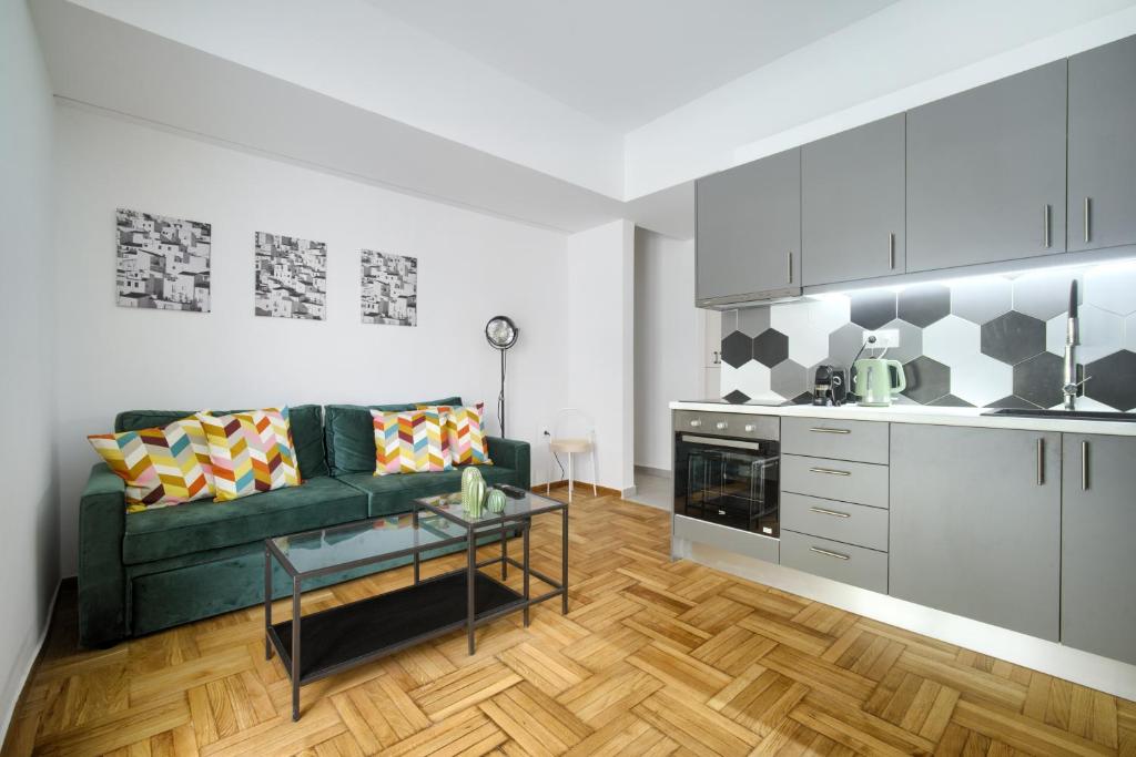 a living room with a green couch and a kitchen at Majestic Flat with Huge Terrace in the City Center in Athens