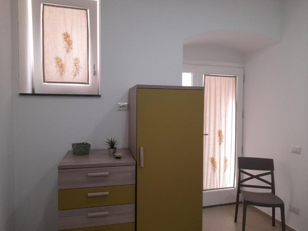 Pokój z zieloną szafką, krzesłem i oknem w obiekcie Ortigia spartan house 3 w Syrakuzach