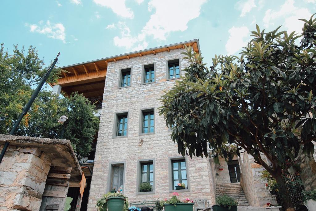 un antiguo edificio de piedra con árboles delante de él en Bujtina Maria en Gjirokastër