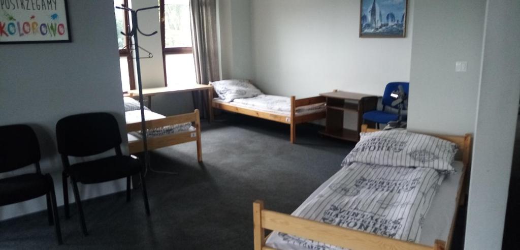 a room with two beds and a desk and chairs at Hostel Sunrise przy DW. Zachodnim in Warsaw