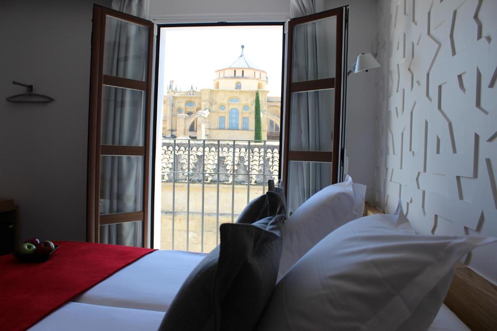 a bed sitting in front of a window in a hotel room at Hotel Boutique Caireles in Córdoba