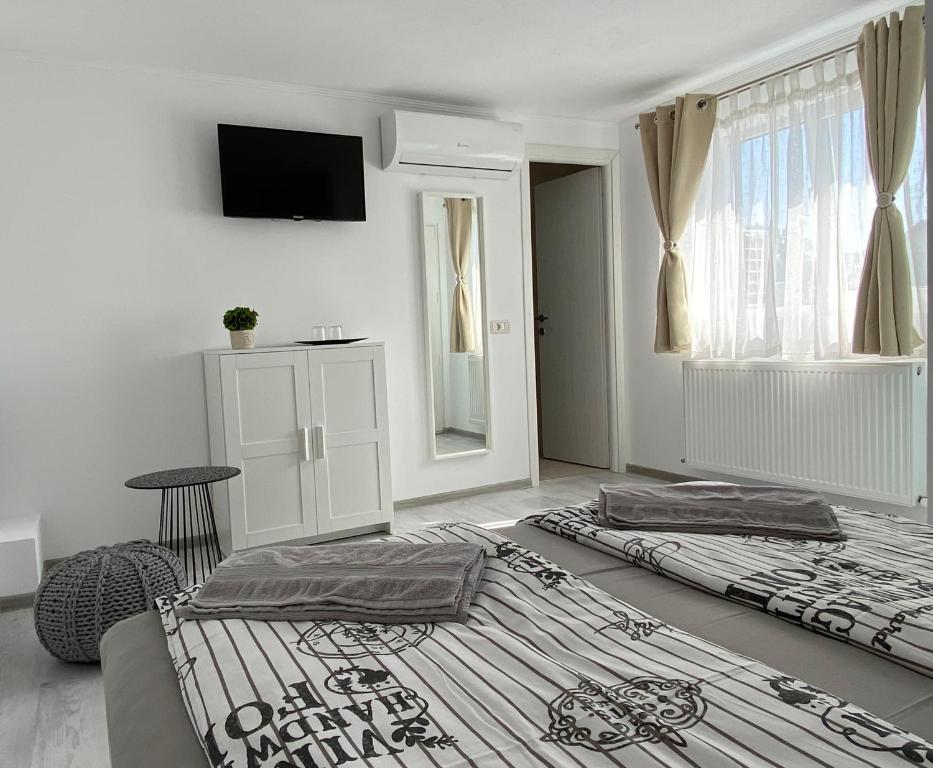 a white room with two beds and a window at Four Rooms in Curtea de Argeş
