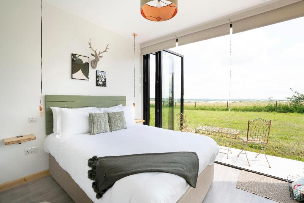 a bedroom with a large bed and a large window at Box6 at West Down in Sherborne