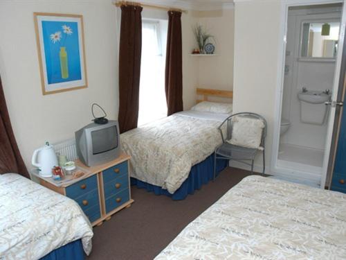 a hotel room with two beds and a television at Kentmere Guest House in Folkestone