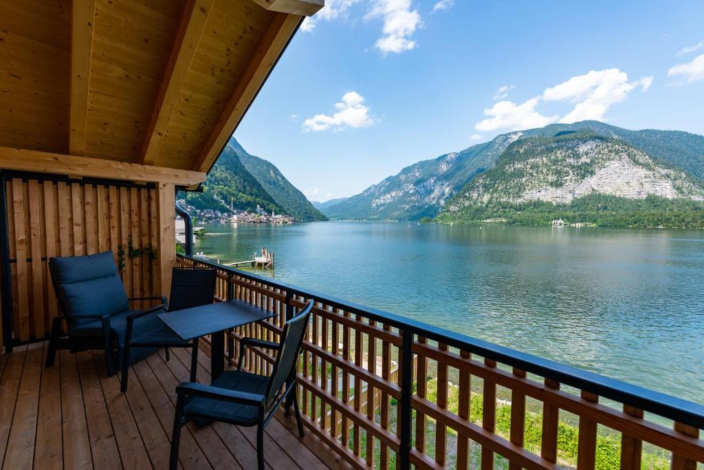 um alpendre com 2 cadeiras, uma mesa e vista para um lago em Boutiquehotel Strand Hallstatt - Adults only em Hallstatt