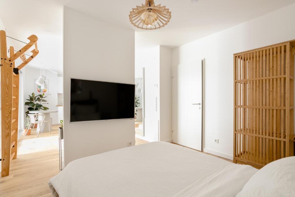um quarto branco com uma cama e uma televisão de ecrã plano em Sweet Suite - Zentrale Wohnung nähe Augarten em Viena