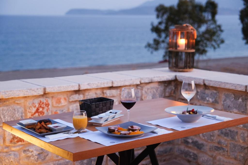a table with two glasses of wine and a plate of food at Margo Beach Hotel in Gythio