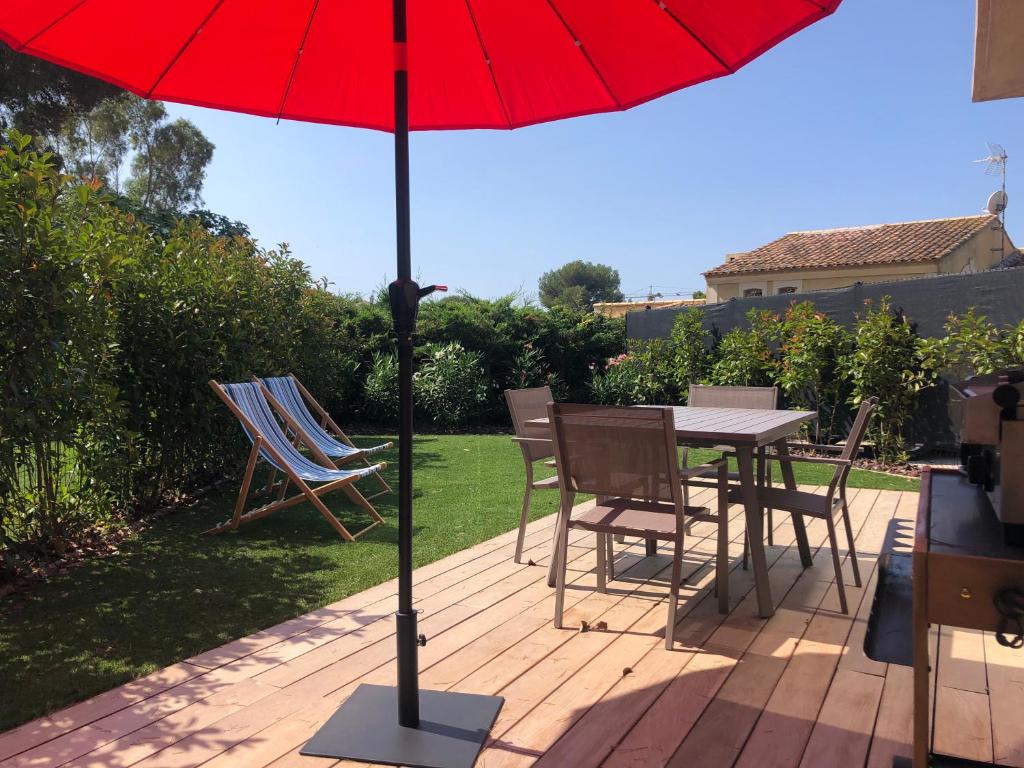 een tafel en stoelen met een rode parasol op een patio bij L'ete Indien 2 in Sanary-sur-Mer