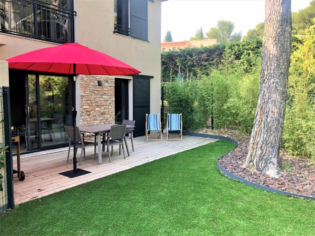 une terrasse en bois avec une table et un parasol rouge dans l'établissement L'ete Indien 1, à Sanary-sur-Mer