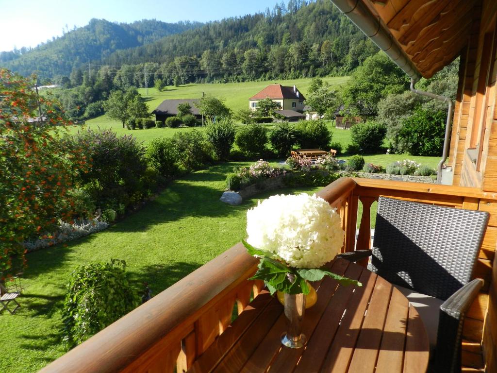 un jarrón de flores sentado en un balcón de madera en Landhaus am Bach, en Übelbach