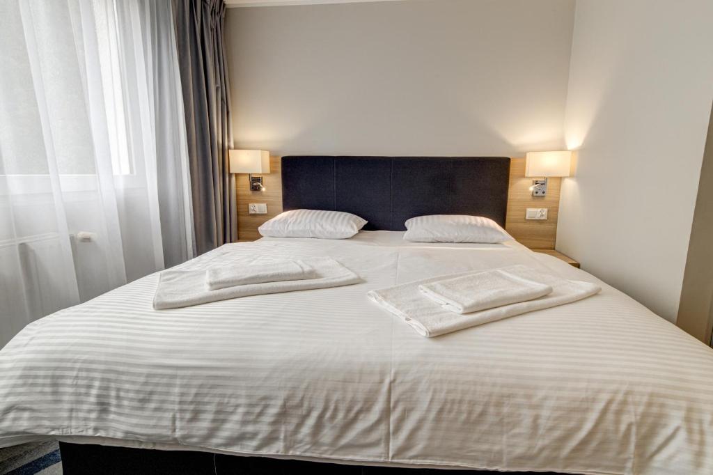 a large white bed with two white towels on it at Hotel Dobosz in Police