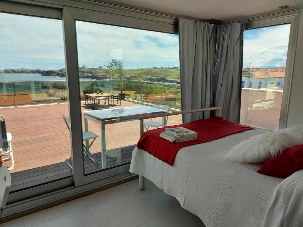 a bedroom with a large window with a view of a deck at Villa Playa San Juan in Soto de la Marina