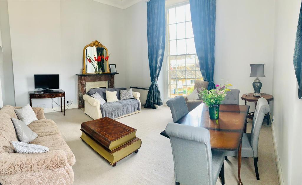 a living room with a table and blue curtains at Alexander House in Corsham