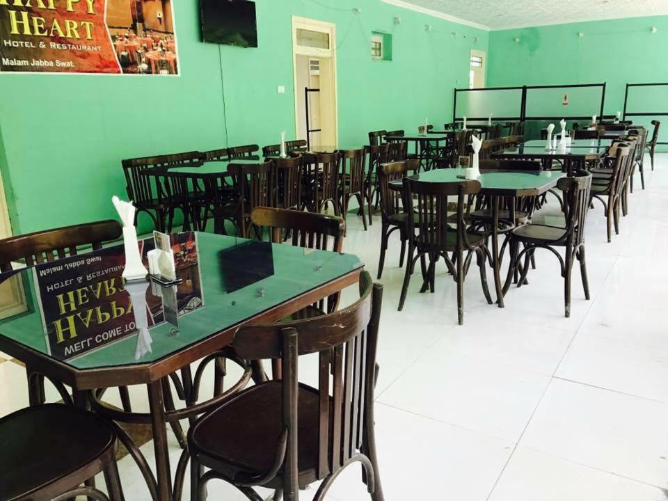 een eetkamer met tafels en stoelen en groene muren bij Happy Heart Hotel & Restaurant in Malam Jabba