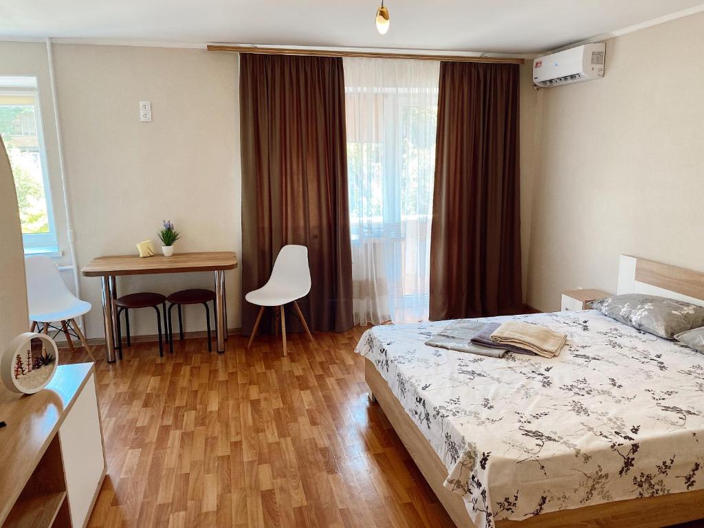 Schlafzimmer mit einem Bett, einem Tisch und einem Schreibtisch in der Unterkunft Apartment Sobornyi Prospect 95 in Saporischschja