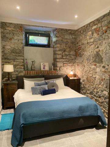 una camera con letto e parete in pietra di Villa Bacchetta - Stone Cottage a Oleggio Castello
