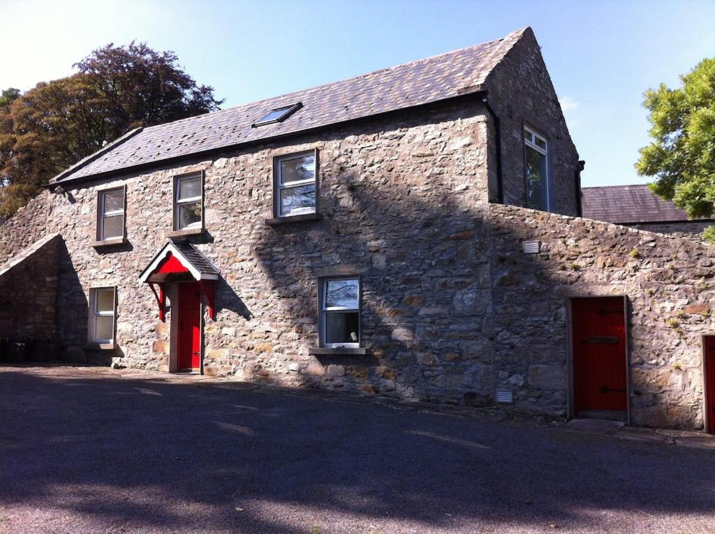 an old stone house with a red door at The Stables - 200 Year Old Stone Built Cottage in Foxford