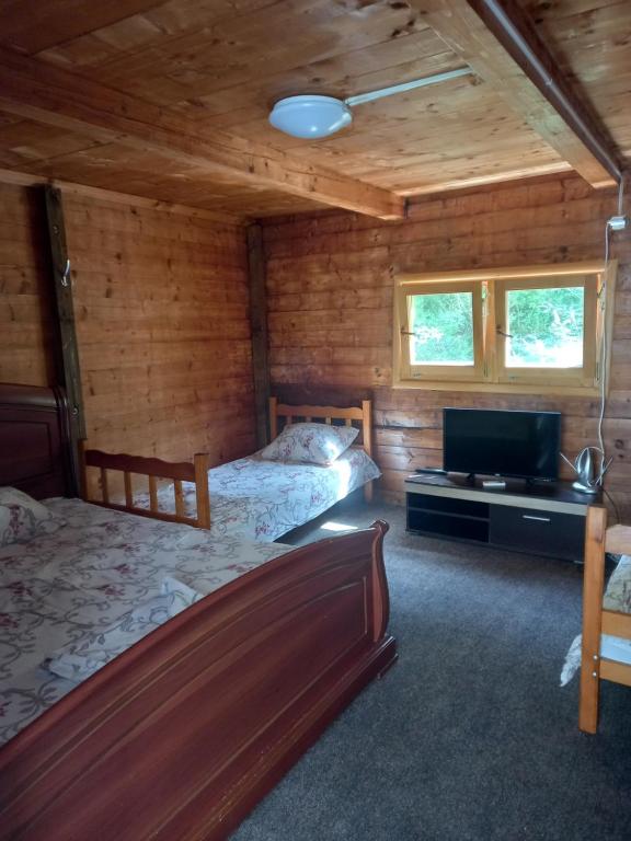 a bedroom with two beds and a flat screen tv at Vikendica in Čanj