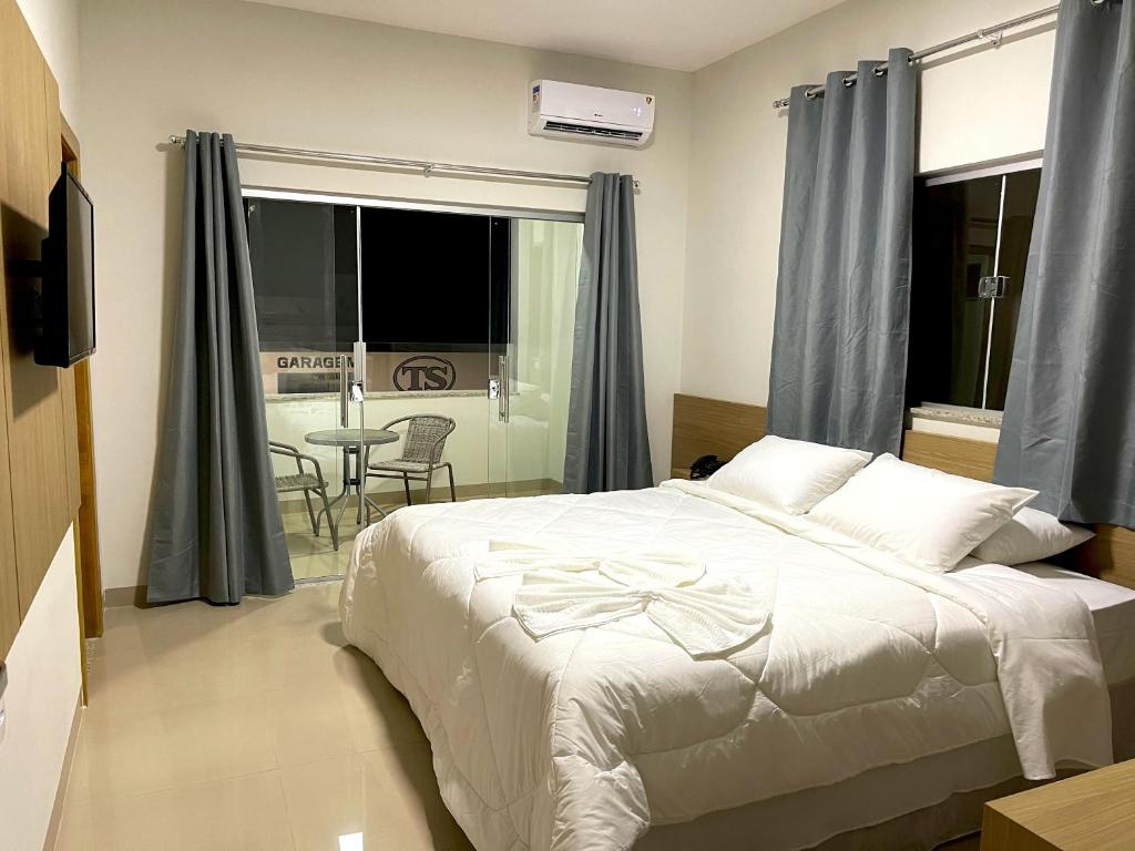 Un dormitorio con una gran cama blanca y una mesa. en TS HOTEL, en Porteirinha