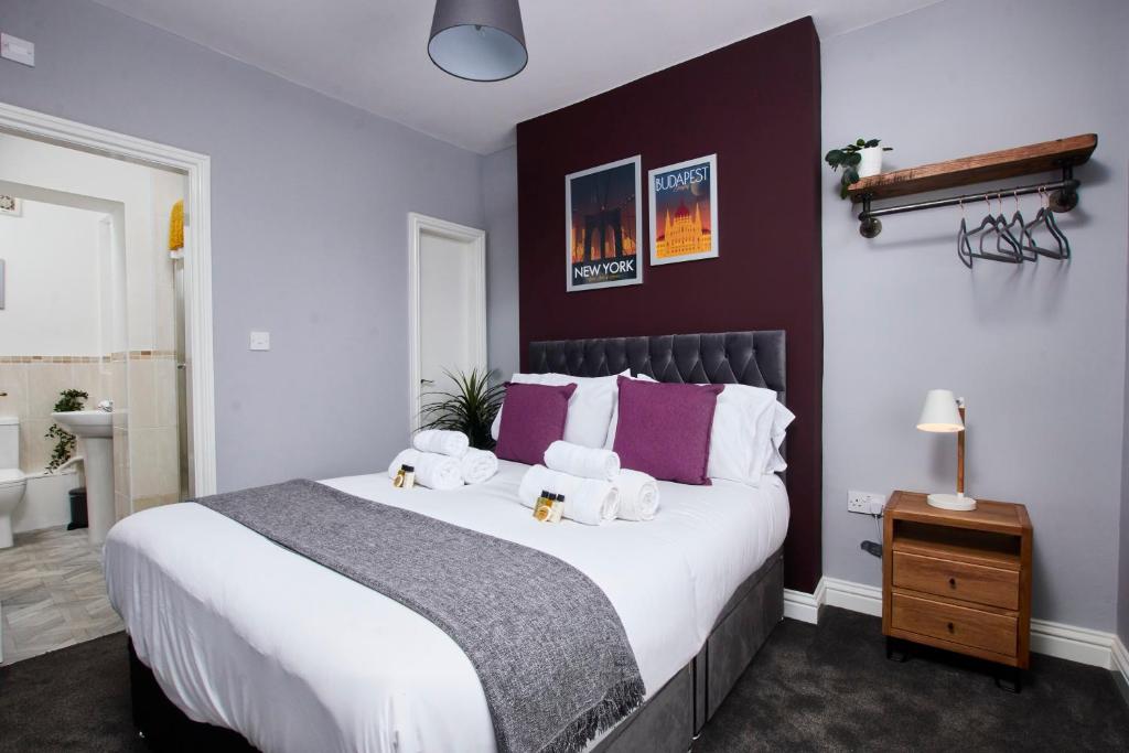 a bedroom with a large white bed with purple walls at Delven House, Apartment 4 in Castle Donington