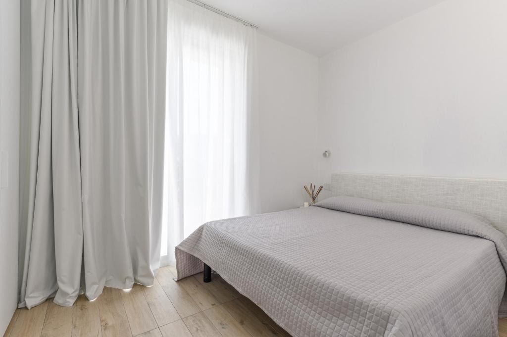 a white bedroom with a bed and a window at Capo Falcone Charming Apartments in Stintino
