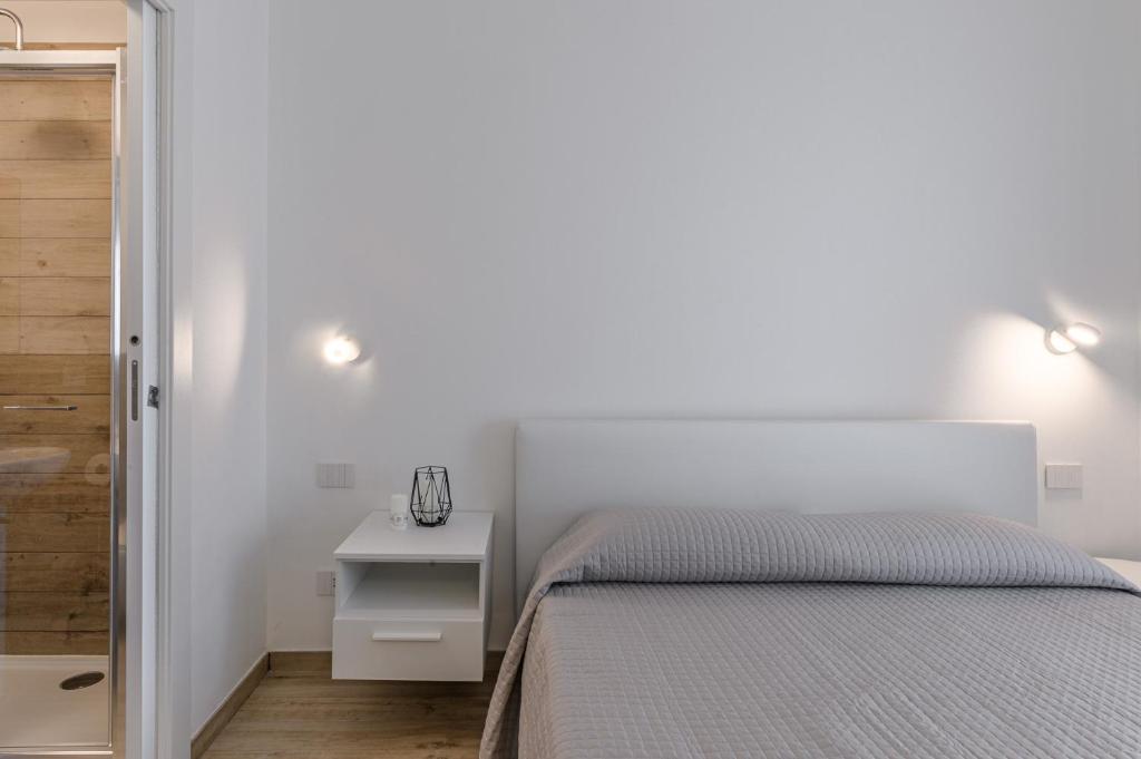 a white bedroom with a bed and a white nightstand at Capo Falcone Charming Apartments in Stintino