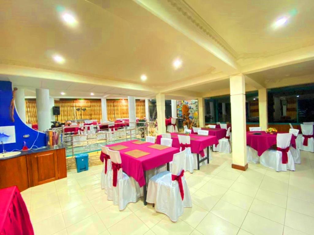 a dining room with pink tables and white chairs at Srilak View Holiday Inn in Haputale