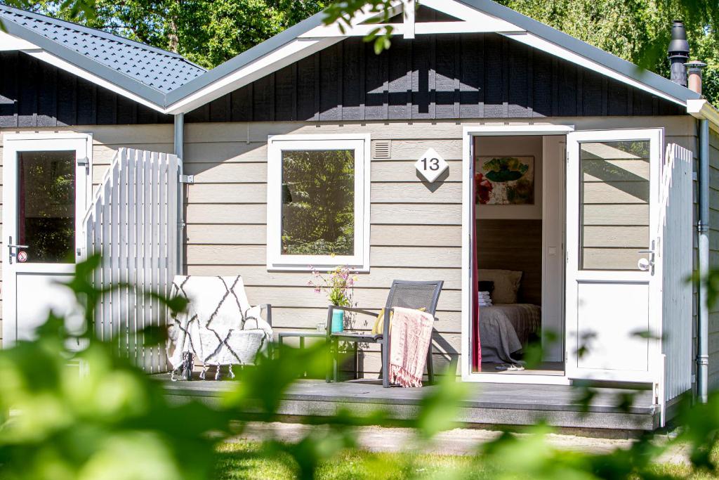 Casa pequeña con porche, mesa y sillas en Vakantiepark Witterzomer Assen, en Assen