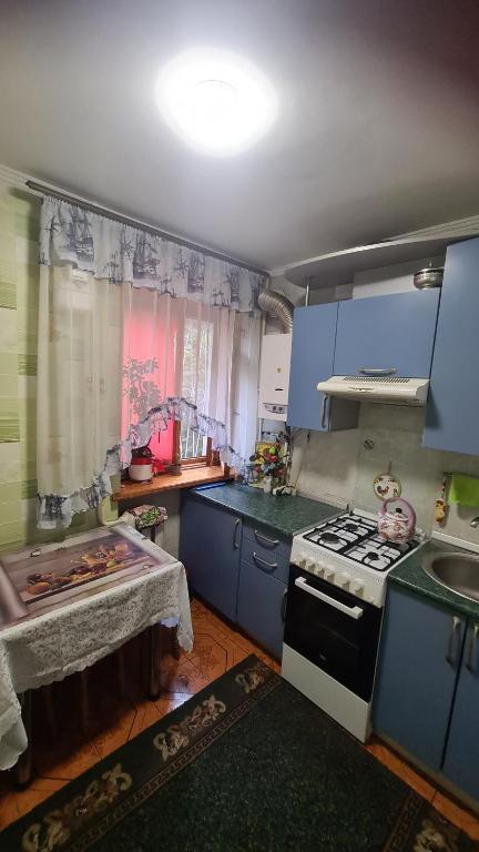 cocina con armarios azules, fogones y fregadero en МЫ Вас ЖДЕМ Апартаменты у МОРЯ, en Odessa