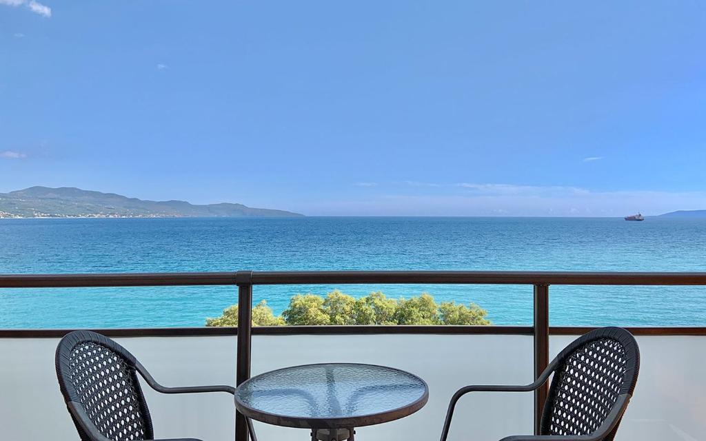 a table and chairs on a balcony overlooking the ocean at Hotel Flisvos in Kalamata