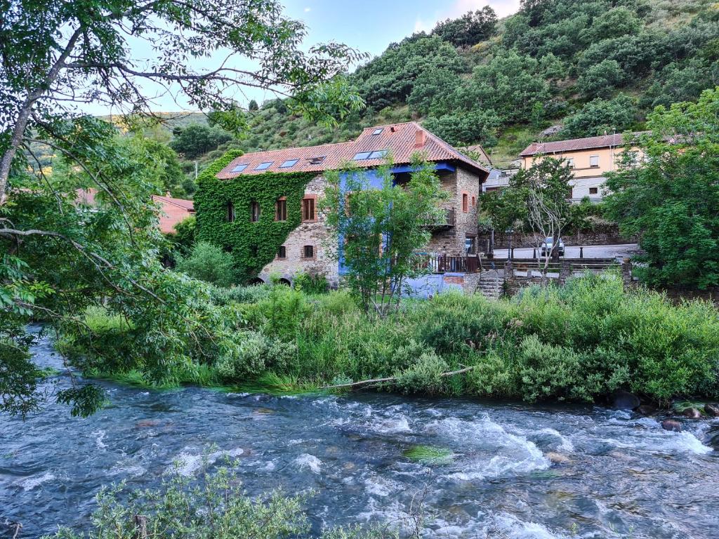 un antiguo edificio junto a un río con una casa en El Molino de la Ropería, en Serrilla