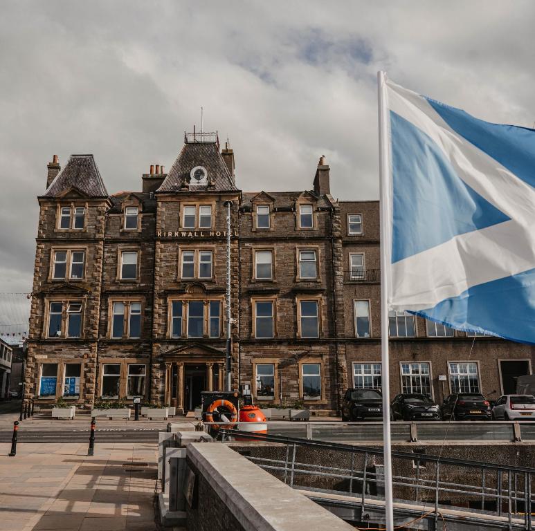 un gran edificio con una bandera delante de él en The Kirkwall Hotel, en Kirkwall