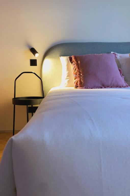 a white bed with a purple pillow and a side table at Oporto CoLiving Monte Ramalde in Porto