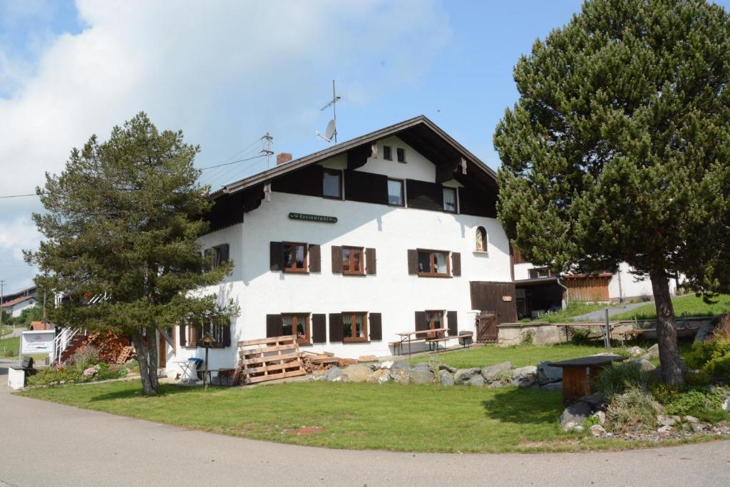 uma grande casa branca com árvores em frente em Alpenblick em Wertach