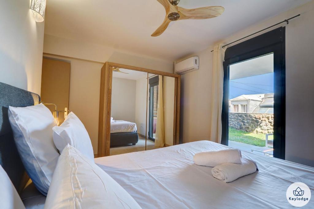 una camera con letto, ventilatore a soffitto e specchio di T3 - Leu Filao, classé 4 étoiles - 70m2 - Plage et Lagon de Saint-Leu a Saint-Leu