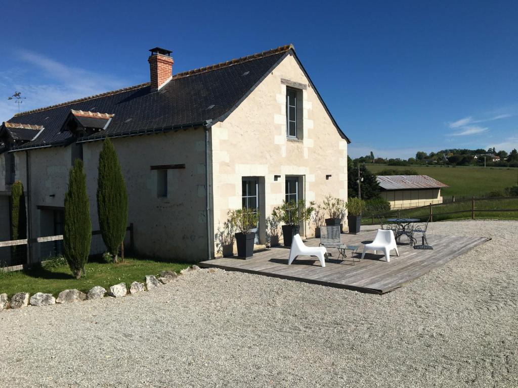 ein Haus mit zwei weißen Stühlen und einer Terrasse in der Unterkunft Les Vallées in Fondettes