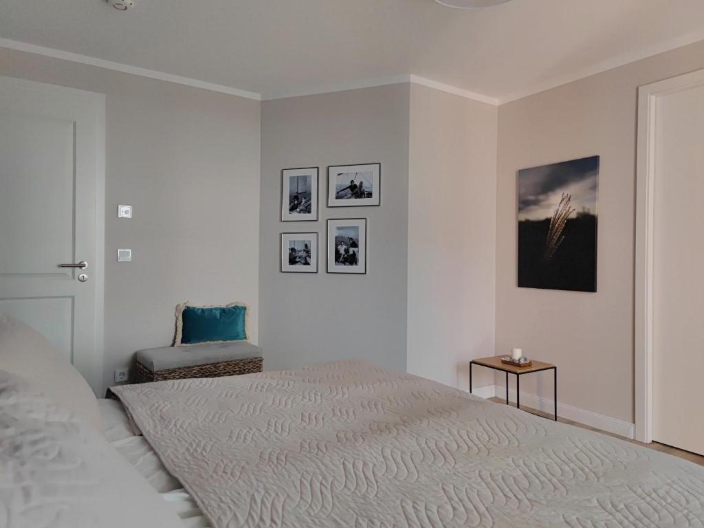 een witte slaapkamer met een bed en een stoel bij Jolle 54 in Putbus