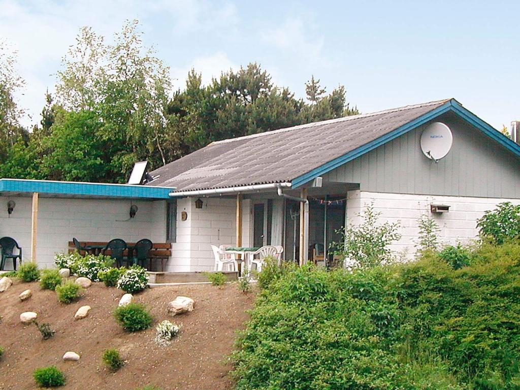 Casa blanca con techo azul y patio en Four-Bedroom Holiday home in Spøttrup 2, en Lihme