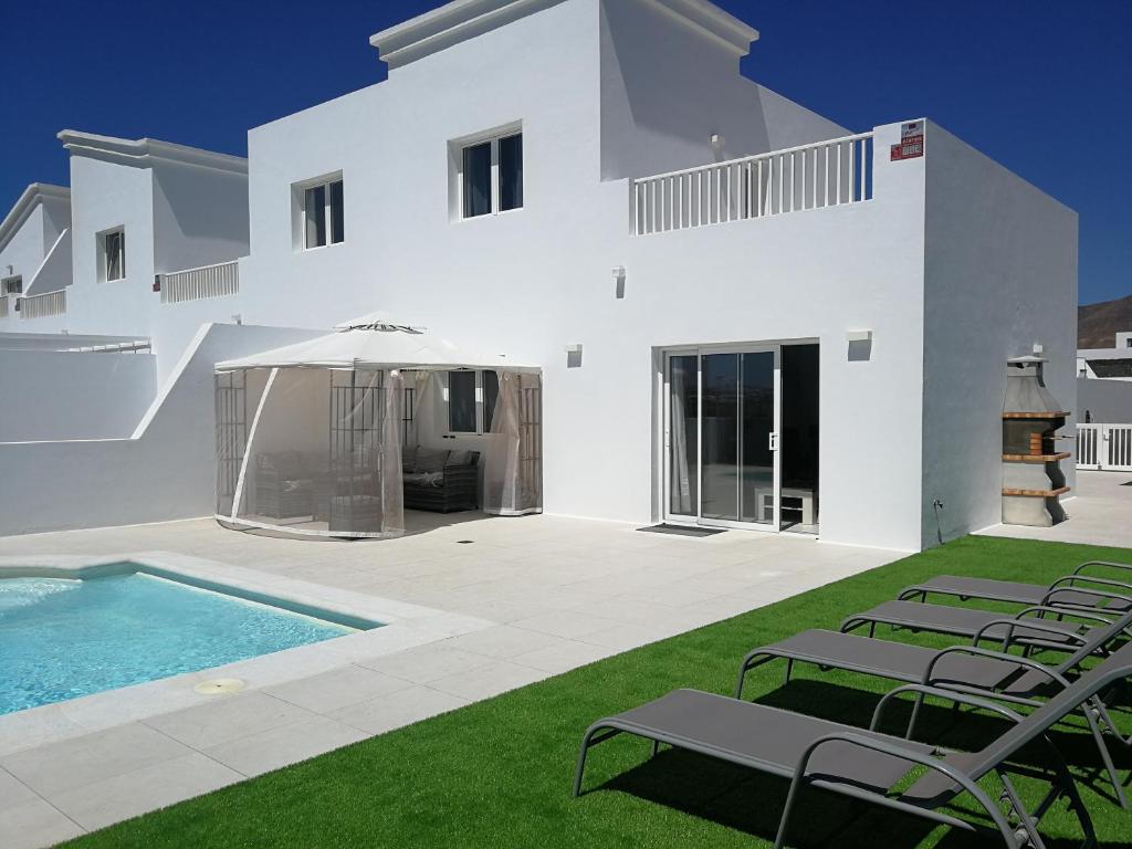 une maison blanche avec piscine et pelouse dans l'établissement Villa Selena, à Playa Blanca