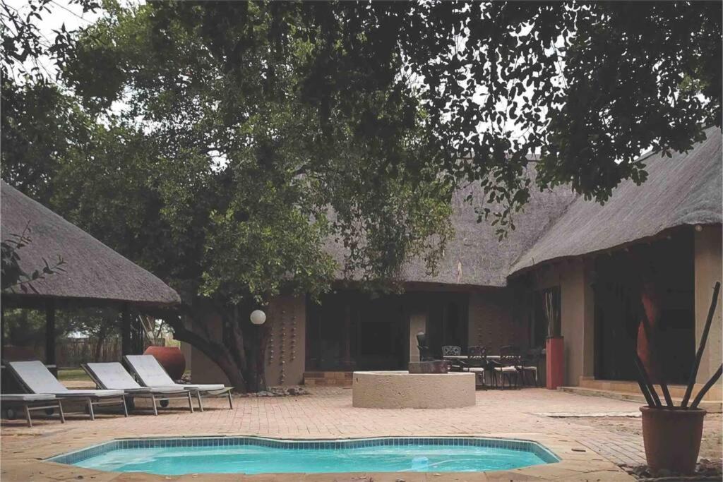 a swimming pool in front of a building with chairs at 86 Zebula 12 Sleeper Lodge in Mabula