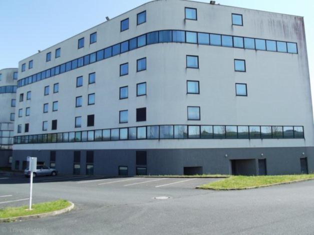 a large white building with a parking lot in front of it at Studio à 8 min à pied du Futuroscope – 1&#47;4 pers in Chasseneuil-du-Poitou